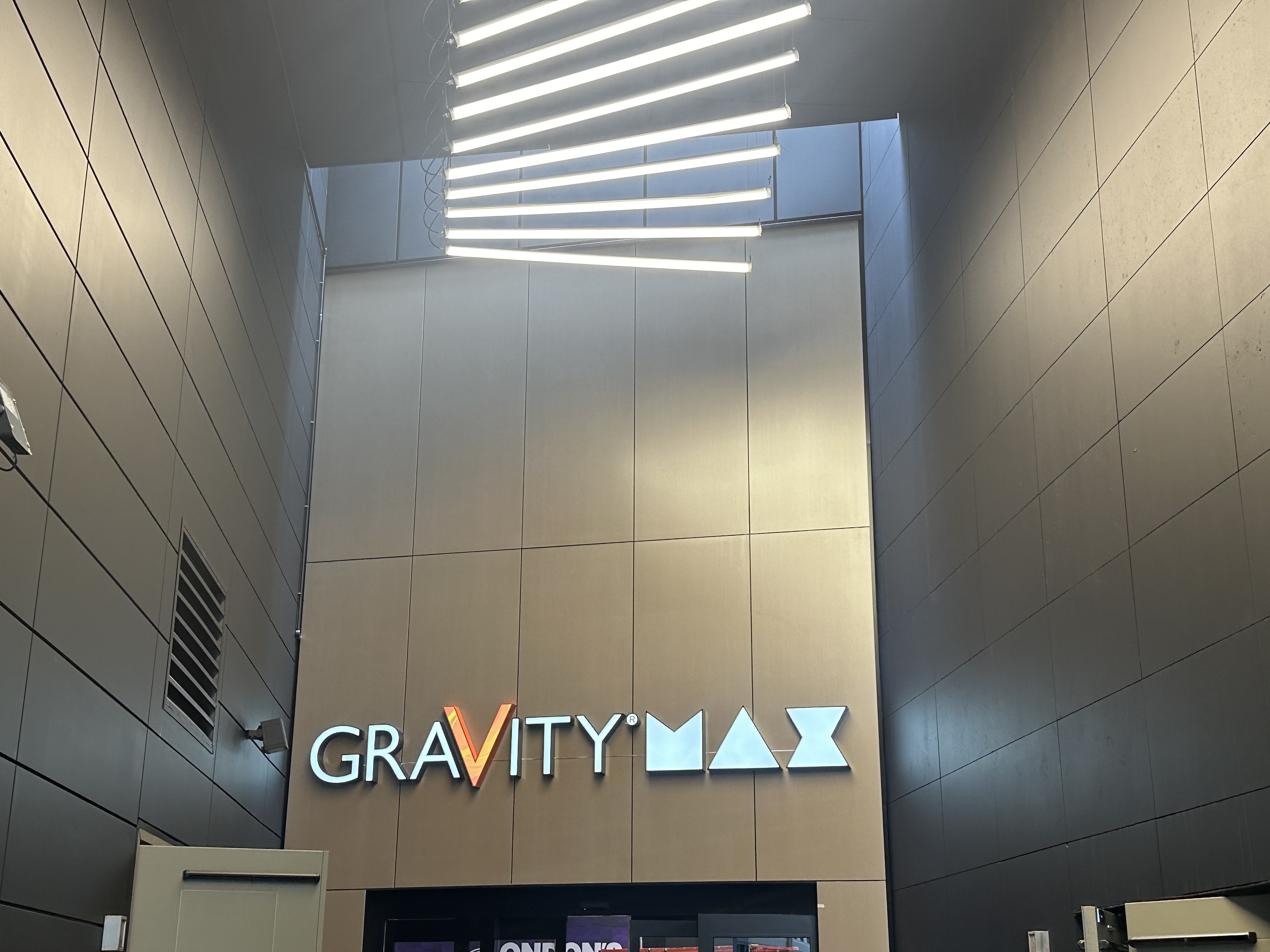 Gravity Max main entrance with illuminated venue signage and a suspended linear LED lighting array